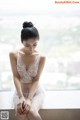 A woman in a white lingerie sitting on a window sill.