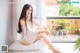 A woman sitting on a window sill in a white lingerie.