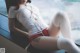 A woman in a white shirt and red shorts sitting on a window sill.