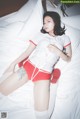 A woman in a white shirt and red shorts laying on a bed.