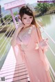 A woman in a pink dress standing on a bridge.