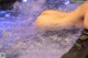 A naked woman in a hot tub with water splashing around her.