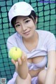 A woman holding a tennis ball in front of a net.