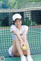 A woman sitting on a tennis court holding a tennis ball.