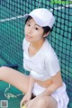 A woman in a white shirt and skirt sitting on a tennis court.