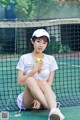 A woman sitting on a tennis court holding a tennis ball.