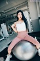 A woman sitting on an exercise ball in a gym.