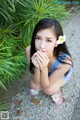 A woman in a blue and white dress crouching down with a flower in her hair.