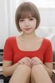 A woman in a red shirt sitting on a couch.