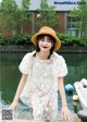 A woman in a white dress and a straw hat posing for a picture.