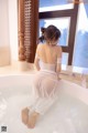 A woman in a white dress sitting in a bathtub.