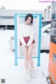 A woman standing in front of a vending machine in the snow.