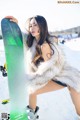 A woman in a fur coat holding a snowboard.