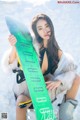 A woman holding a snowboard in the snow.