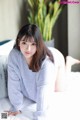 A woman laying on top of a bed next to a plant.