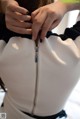 A woman is putting a zipper on a white bag.