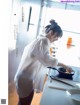 A woman in a white shirt is cooking in a pan.