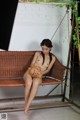 A naked woman sitting on a swing holding a teddy bear.