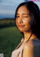 A woman with her eyes closed in a field.