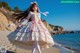 A woman in a pink and white dress standing on a beach.