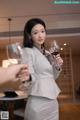 A woman in a business suit holding a glass of wine.