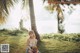 A woman sitting on the grass with a coconut in her hand.