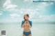 A woman in a blue bikini standing in the ocean.