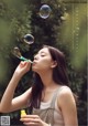 A woman blowing bubbles in front of a green background.