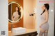 A woman standing in front of a mirror in a bathroom.