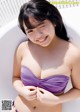 A woman in a purple bikini sitting in a bathtub.