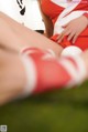 A woman in a red and white outfit is sitting on the grass.