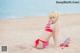 A woman in a red and white bikini laying on the beach.