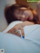 A woman laying in bed with a ring on her finger.