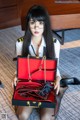 A woman sitting on the floor holding a red purse.