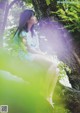 A woman sitting on a tree branch in the woods.