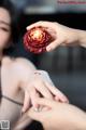 A woman holding a red rose in her hand.