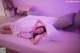 A woman laying on a bed in a room with purple lighting.