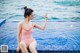 A woman in a pink bathing suit sitting on the edge of a swimming pool.