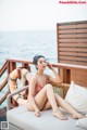 A woman in a pink bathing suit sitting on a white couch.