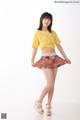 A woman in a yellow shirt and a colorful skirt.