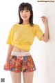 A young woman wearing a yellow shirt and a colorful skirt.