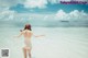 A woman in a white bathing suit standing in the ocean.