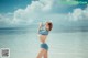 A woman in a blue bikini standing on the beach.