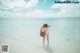 A woman standing in shallow water on a beach.