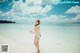 A woman in a pink bathing suit standing on a beach.