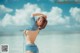 A woman in a blue bikini standing on the beach.