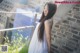 A woman in a white dress standing on a balcony.