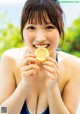 A woman in a blue bikini holding a slice of lemon.