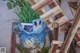 A blue vase with a plant in it sitting on a wooden chair.