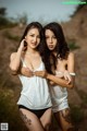 Two young women standing next to each other on a dirt road.